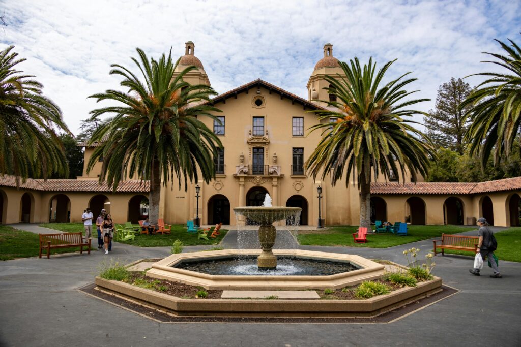 Home A vibrant courtyard at a renowned university featuring palm trees, benches, and a traditional fountain.